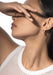 Profile of model covering eyes with hand and wearing a Messika Move 18KYG Pavé Diamond Hoop Earring