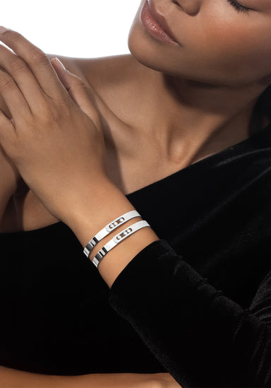 Closeup of a Black model wearing two Messika Move Noa 18K White Gold Pavé Diamond Bangles on wrist