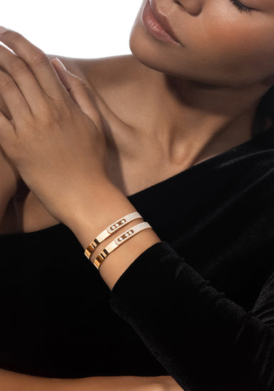 Closeup of a Black model wearing two Messika Move Noa 18K Yellow Gold Pavé Diamond Bangles on wrist