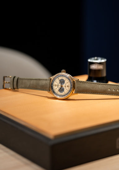 A stylized shot of the Angelus Chronographe Tachymètre Yellow Gold on its side on a wood box