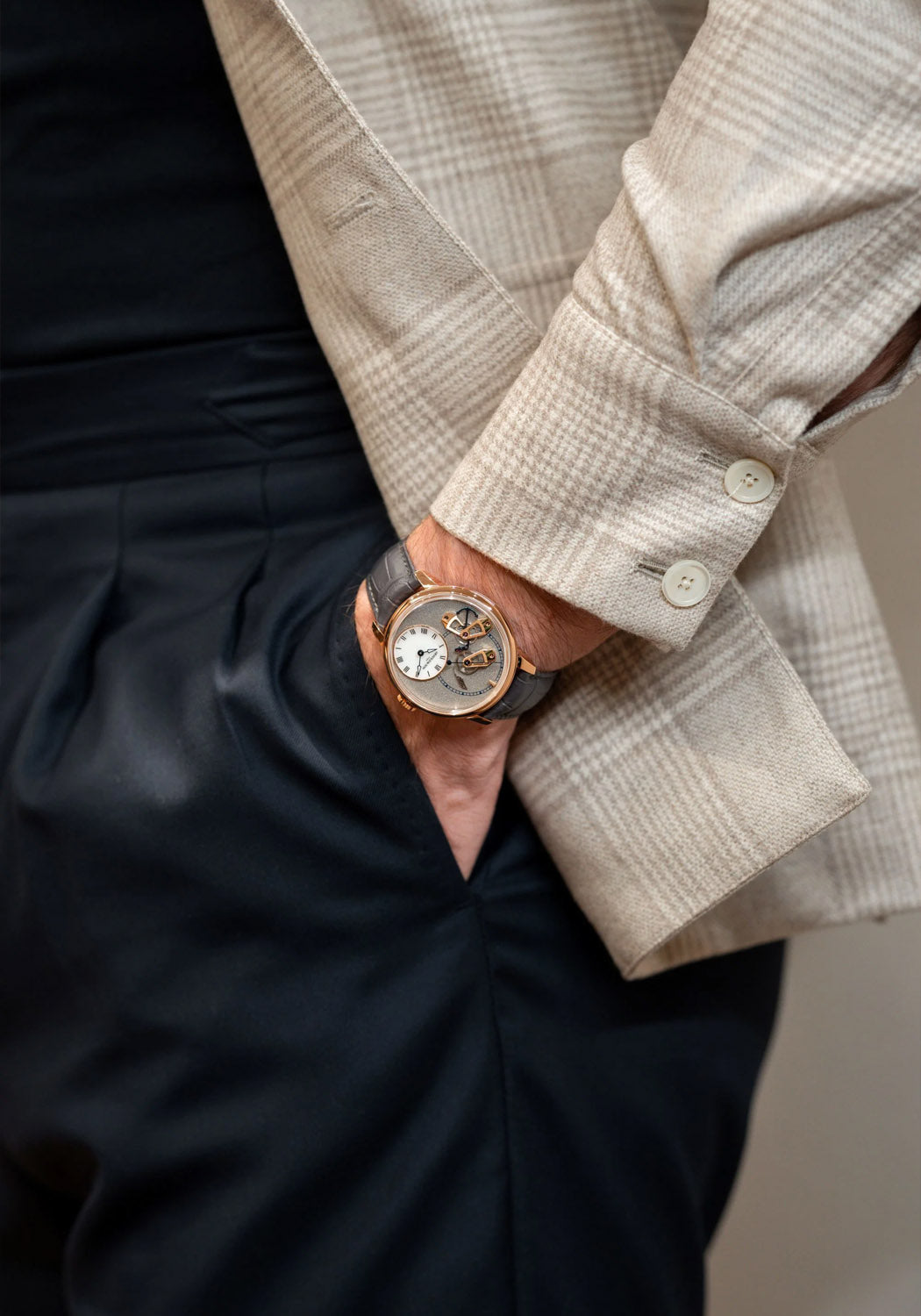 The Arnold & Son DSTB Stop-Seconds Red Gold Cliff Grey on a man's wrist with his hand in his pocket
