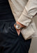 The Arnold & Son DSTB Stop-Seconds Red Gold Cliff Grey on a man's wrist with his hand in his pocket