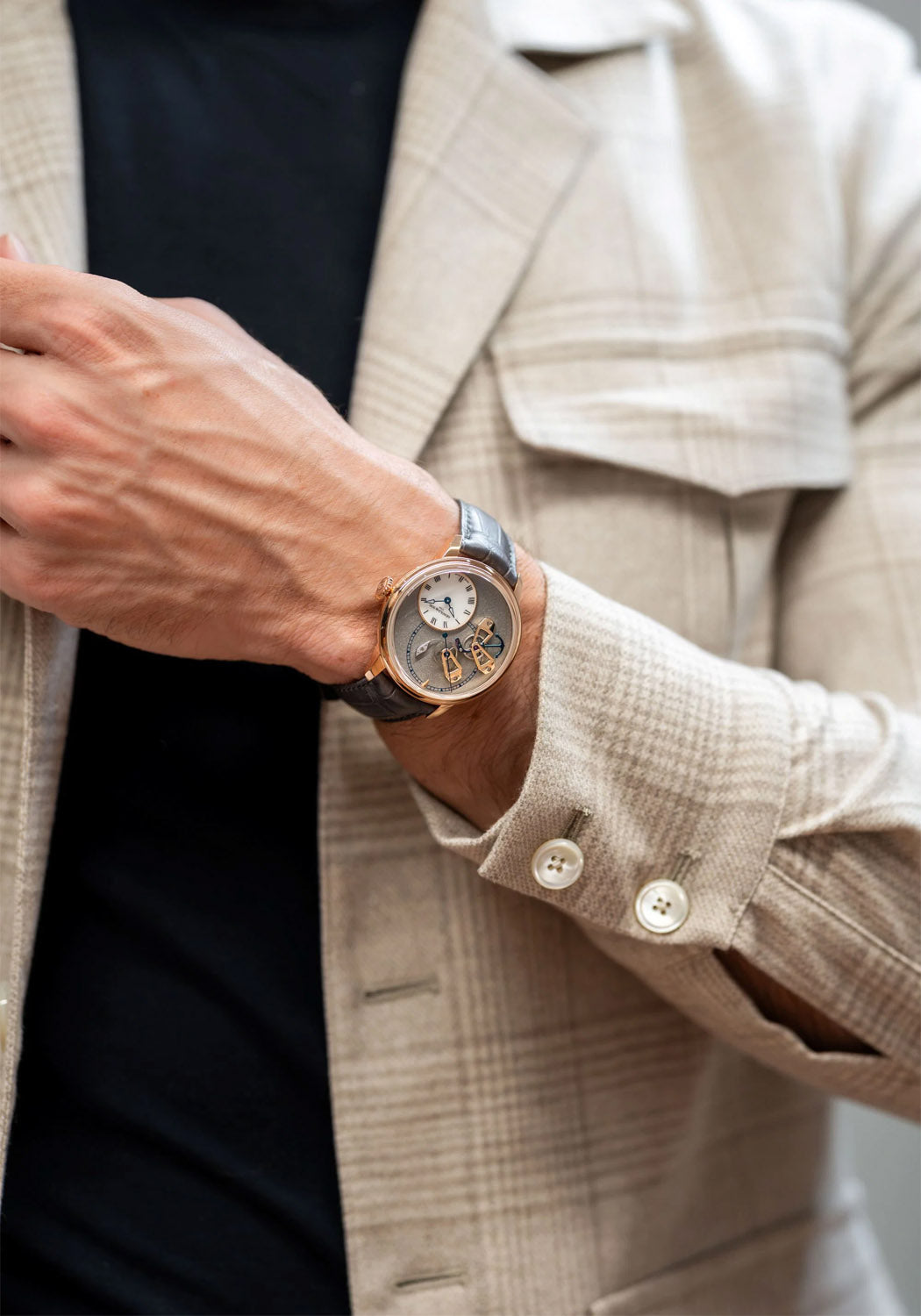 The Arnold & Son DSTB Stop-Seconds Red Gold Cliff Grey on a man's wrist wearing a beige jacket
