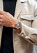 The Arnold & Son DSTB Stop-Seconds Red Gold Cliff Grey on a man's wrist wearing a beige jacket