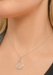 A close-up of a model's neck and collarbone wearing a delicate white gold chain necklace with a teardrop-shaped pendant studded with baguette diamonds