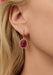 Blonde Woman wearing a slightly oval ruby earring surrounded by diamonds in 14 rose gold. Osterjewelers.com