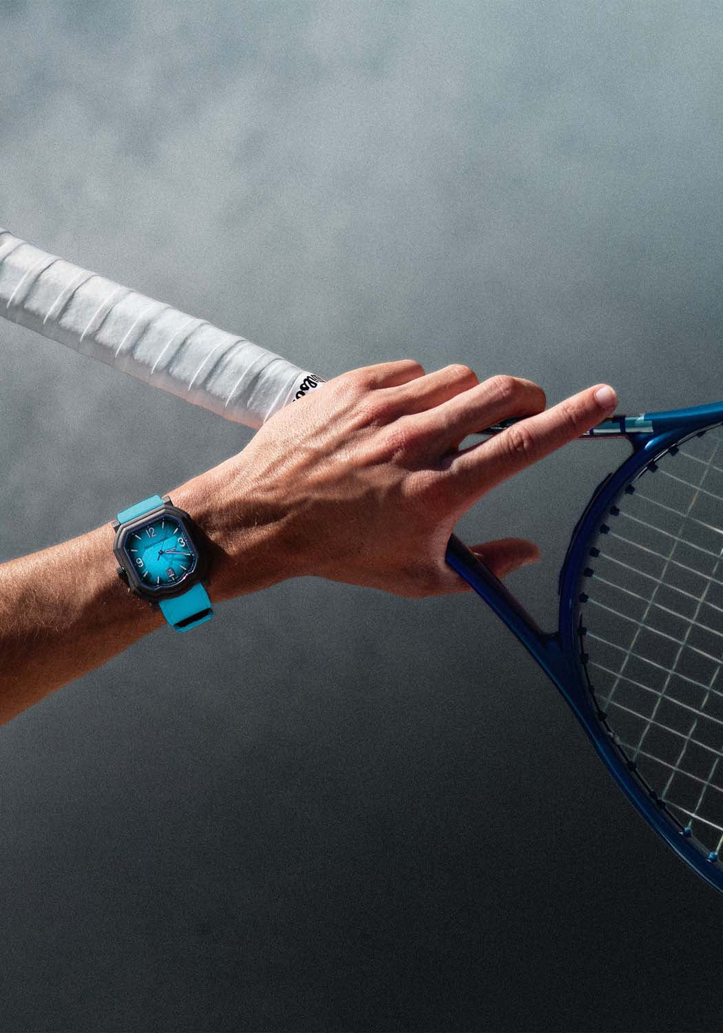 The Gerald Charles Maestro GC Sport Tennis Light Turquoise on a man's wrist holding a tennis racket