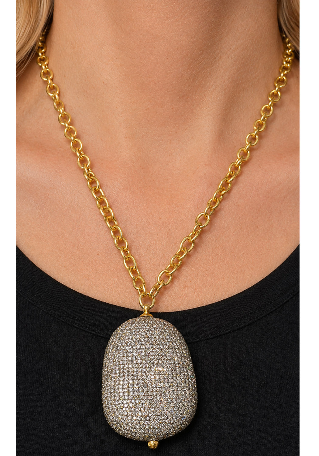 Model wearing large pavé diamond pendant on yellow gold chain.