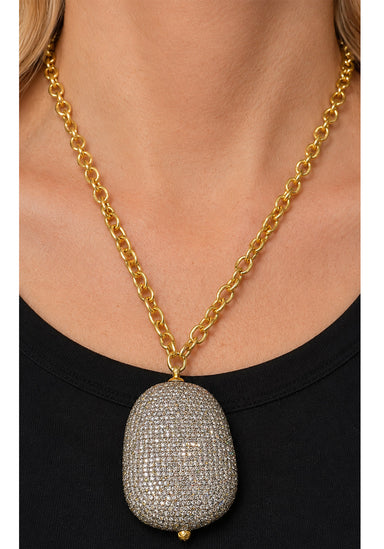 Model wearing large pavé diamond pendant on yellow gold chain.