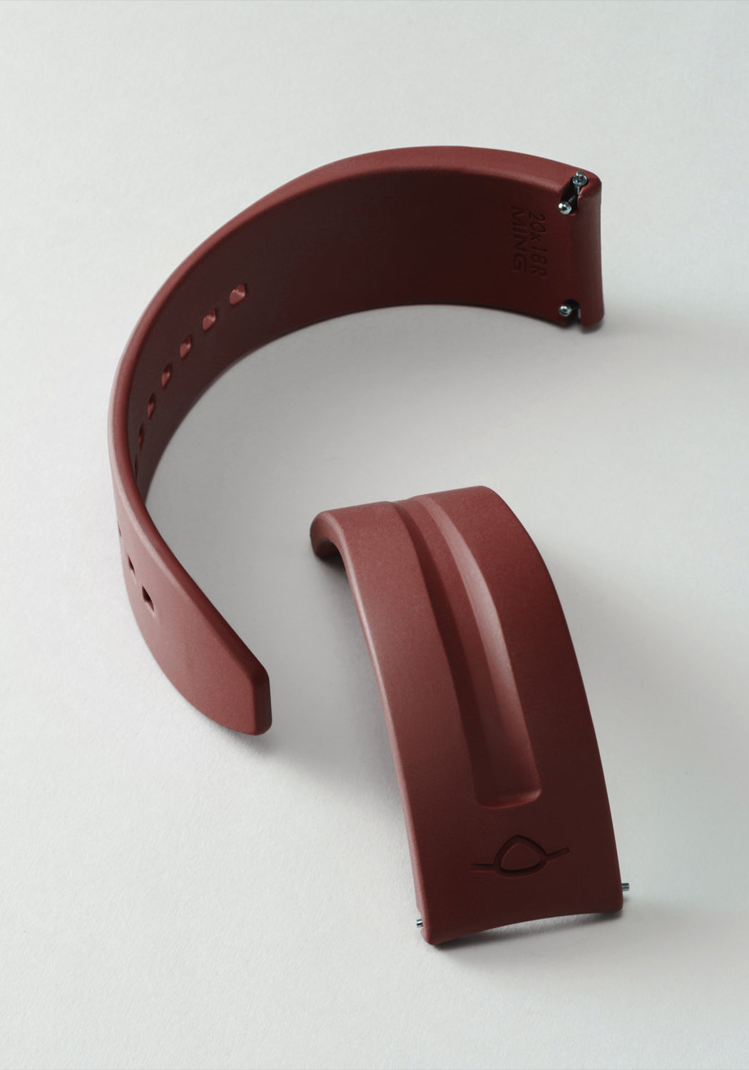 The MING FKM Brick Red Rubber Strap shown on its side in two separate pieces on a light background.