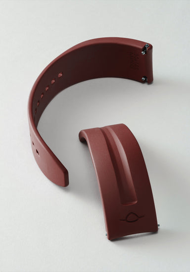 The MING FKM Brick Red Rubber Strap shown on its side in two separate pieces on a light background.