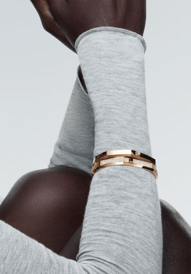 Messika Moderniste 18KRG Large Pavé Diamond Bangle on the wrist of a Black model in a grey sweater