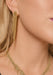 Close-up of a model wearing gold fringe necklace and long dangling gold earrings with a textured, glittery fringe design.
