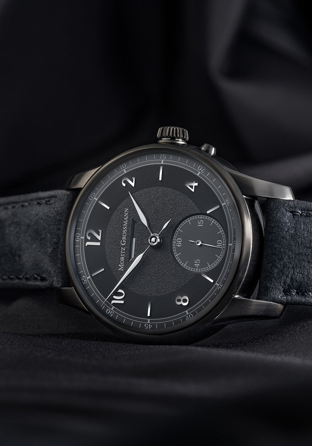 The Moritz Grossmann Benu Power Reserve Black Stainless Steel on a black background