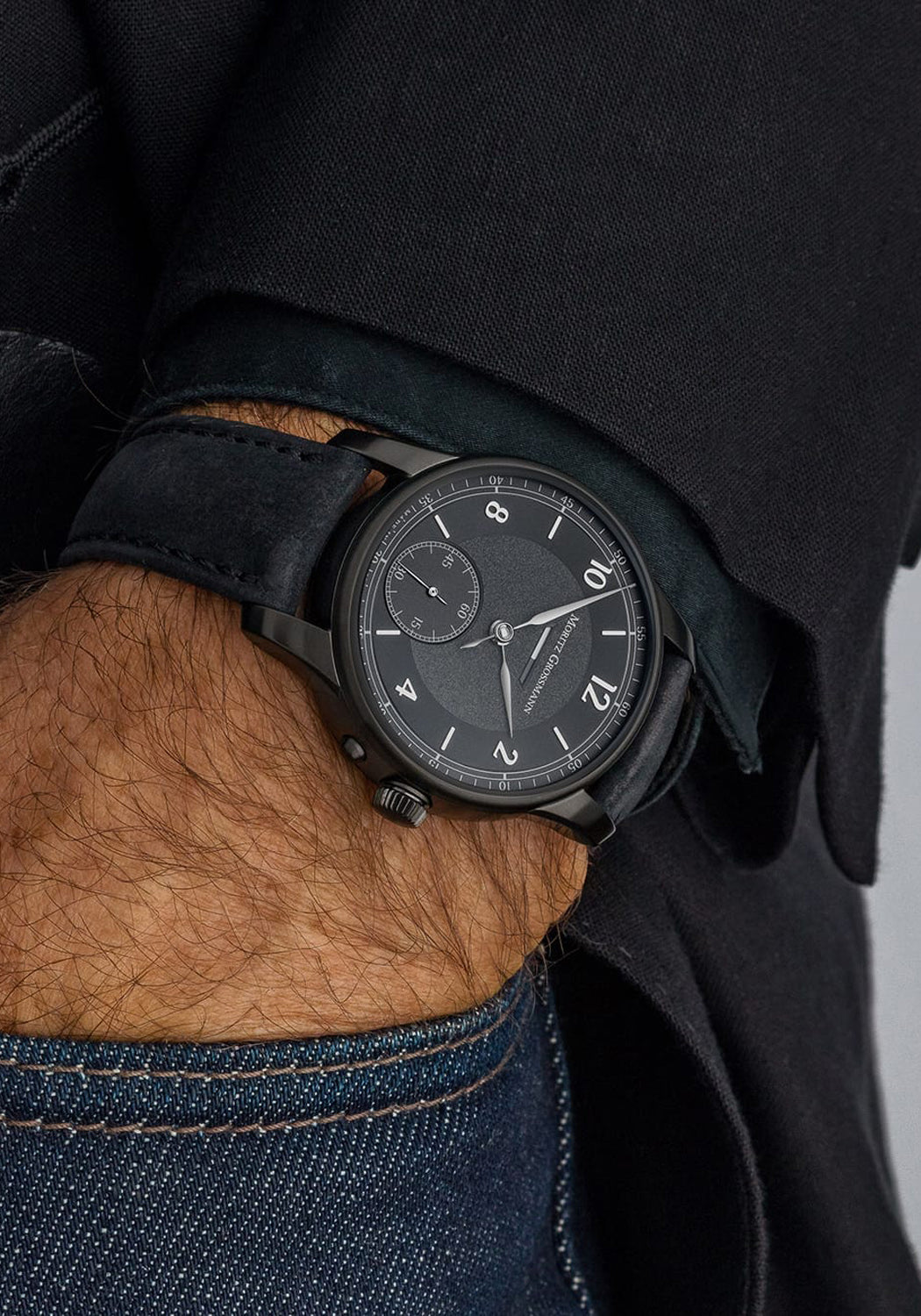 Moritz Grossmann Benu Power Reserve Black Stainless Steel DLC on a man's wrist with hand in pocket