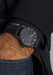 Moritz Grossmann Benu Power Reserve Black Stainless Steel DLC on a man's wrist with hand in pocket