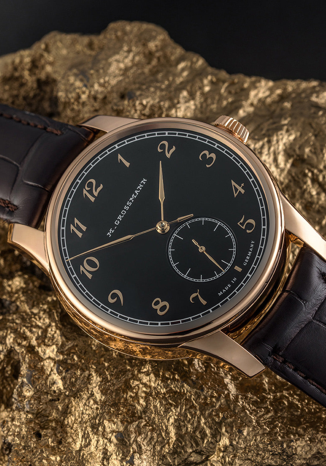 The Moritz Grossmann Hamatic Enamel Rose Gold displayed on a gold rock | OsterJewelers.com