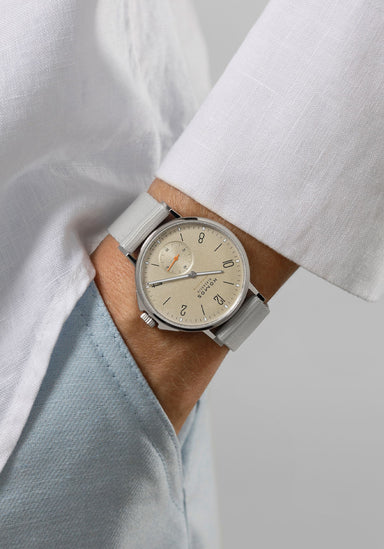 The NOMOS Ahoi Neomatik Sand features a light golden dial. Shown on a woman's wrist.