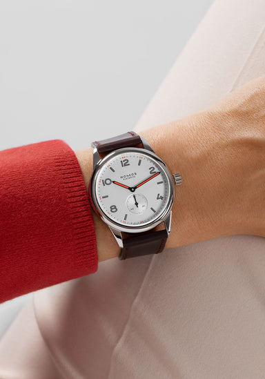 The clean dial of the NOMOS Club 38 flatters every gender. Shown on a woman's wrist.