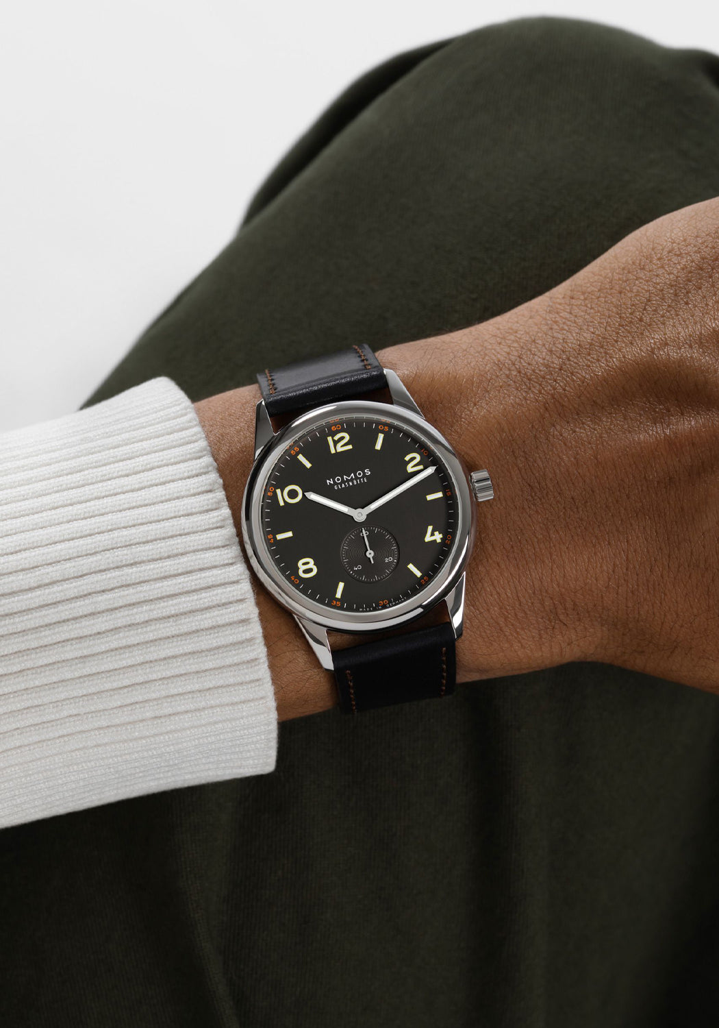 The clean dial of the NOMOS Club 38 flatters every gender. Shown on a man's wrist.