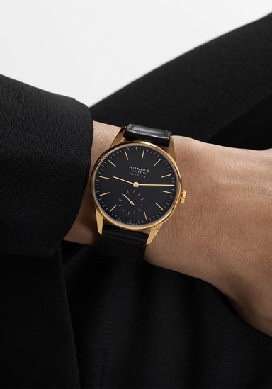 The NOMOS Orion Gold Neomatik New Black 36mm shines on the wrist with its black dial & gold accents

