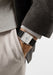 Shown on a man's wrist, the NOMOS Tetra 27 Duo features a small grey square in side a white dial.