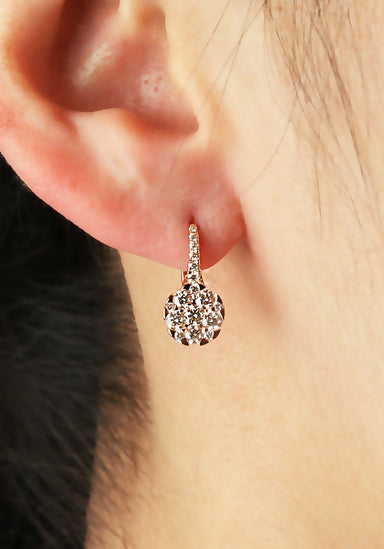 A closeup of a single Parade Design 18KRG Diamond Cluster Drop Earring on a model's ear