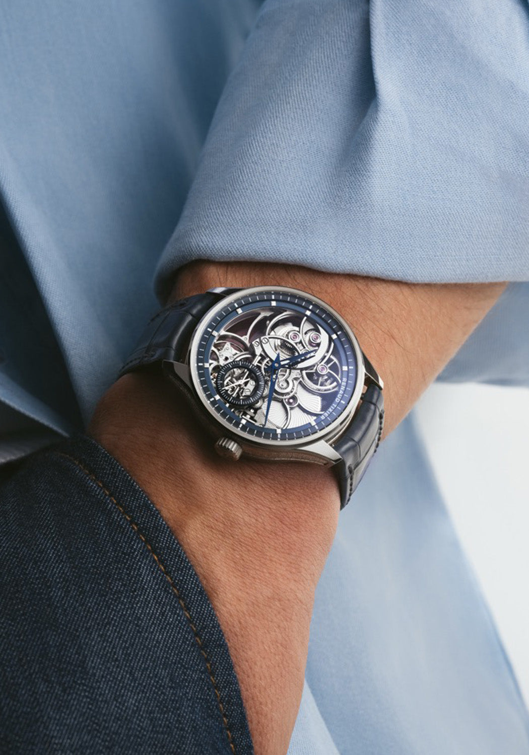 The Renaud Tixier Monday Skeleton Blue on a man's wrist wearing a blue shirt and denim jeans