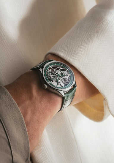 The Renaud Tixier Monday Skeleton Green on a man's wrist wearing a cream shirt and khaki pants.