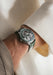 The Renaud Tixier Monday Skeleton Green on a man's wrist wearing a cream shirt and khaki pants.