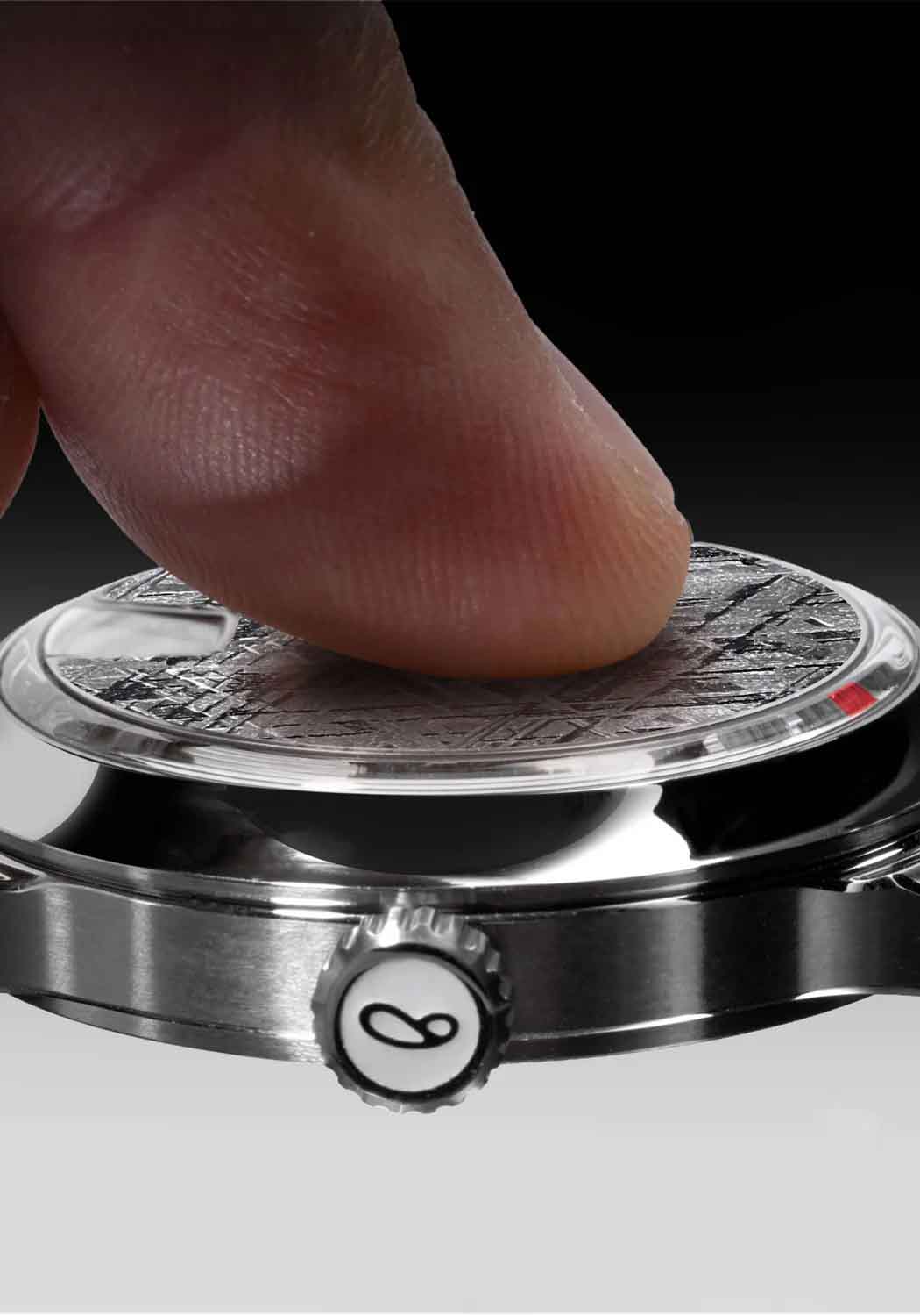Close up of a finger touching the face of the SB 10 Jumping Hour Meteorite watch.