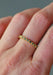 The Sethi Couture Bezel Mini Green Sapphire Eternity Band on a model's hand highlights the green hue