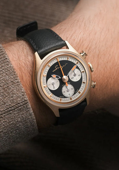 The Singer Reimagined Heritage V72 Gold on a man's wrist. It features a black grained leather strap.