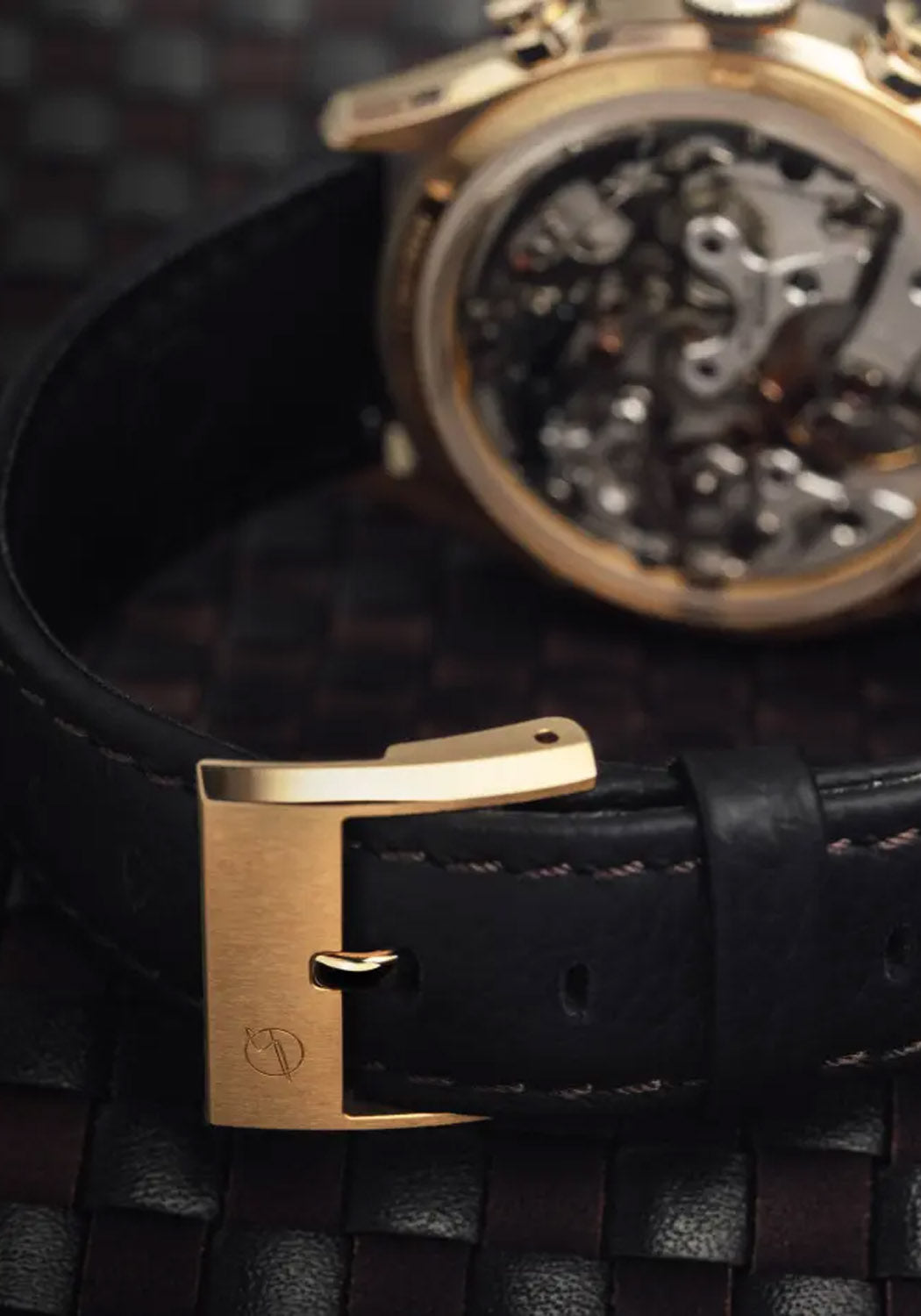 A closeup of the black grained natural leather with Testa di Moro brown stitching and gold buckle.
