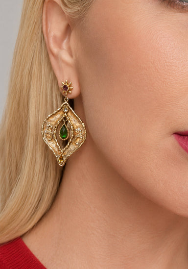 Blonde woman wearing large gold and white Victor Velyan Chrome Diopside & Pink Sapphire Dangle Earring from Osterjewelers.com