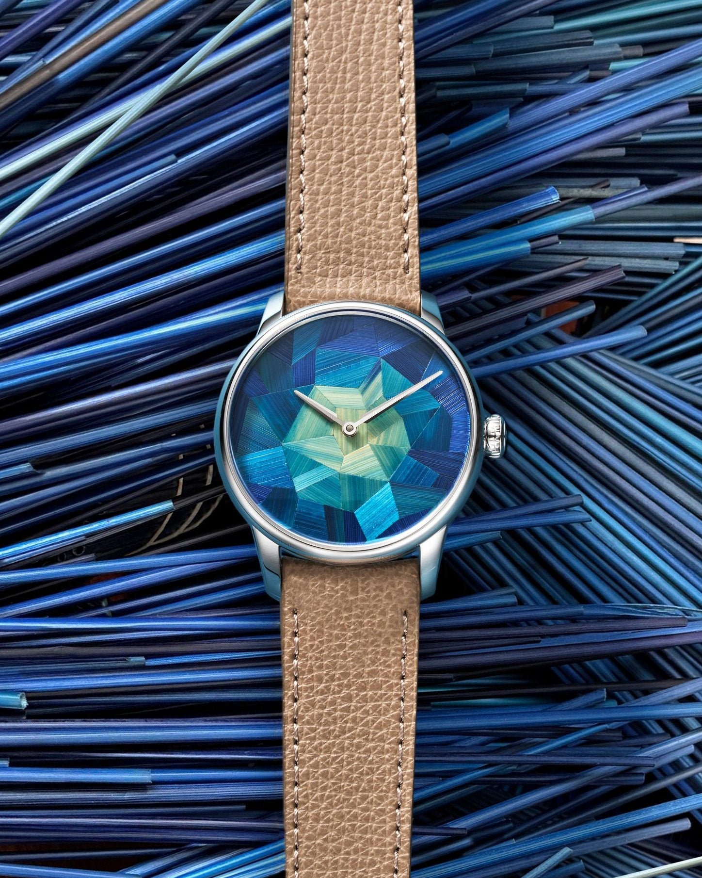 Louis Erard Marqueterie de Paille shown against the blue straw used in crafting the marquetry dial.