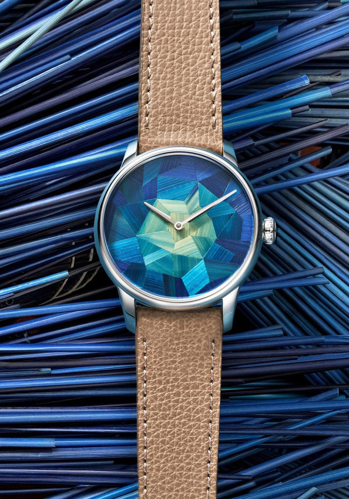 Louis Erard Marqueterie de Paille shown against the blue straw used in crafting the marquetry dial.